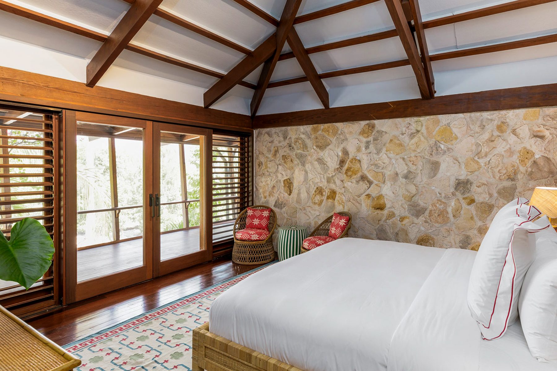 A bedroom with stone wall and doors onto the deck