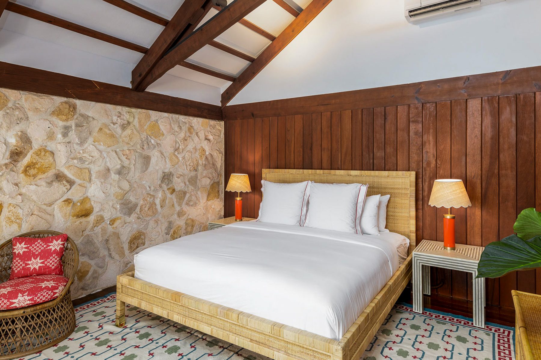 A bedroom with rattan bed and stone wall